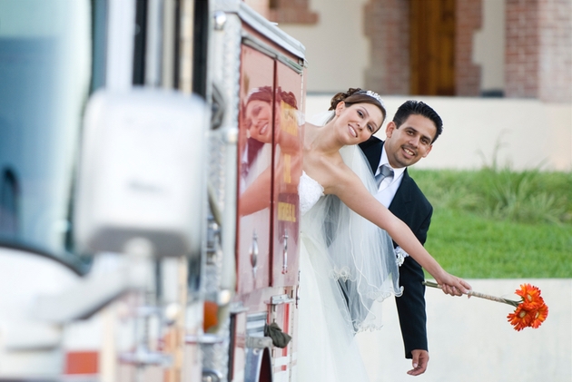 Bride and groom hang from the back of a fire engine