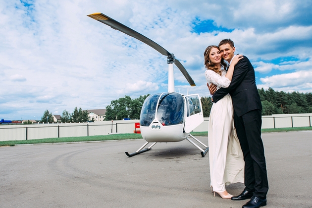 Bride and groom embrace by a helicopter