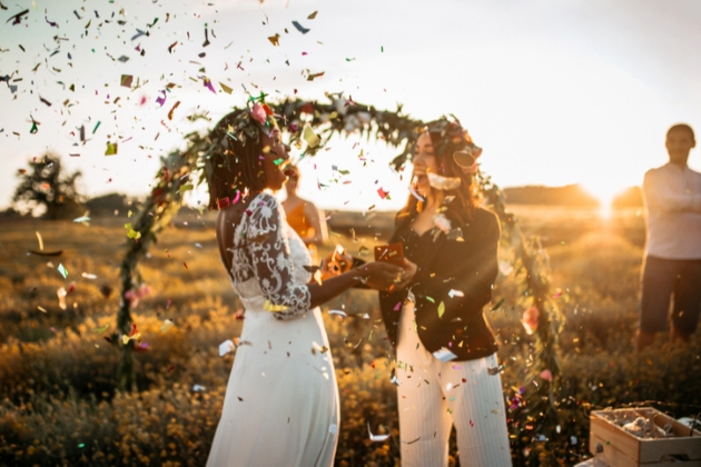 Brides celebrate in confetti at outdoor wedding