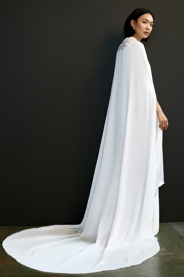 Model is wearing a floor-length white cape