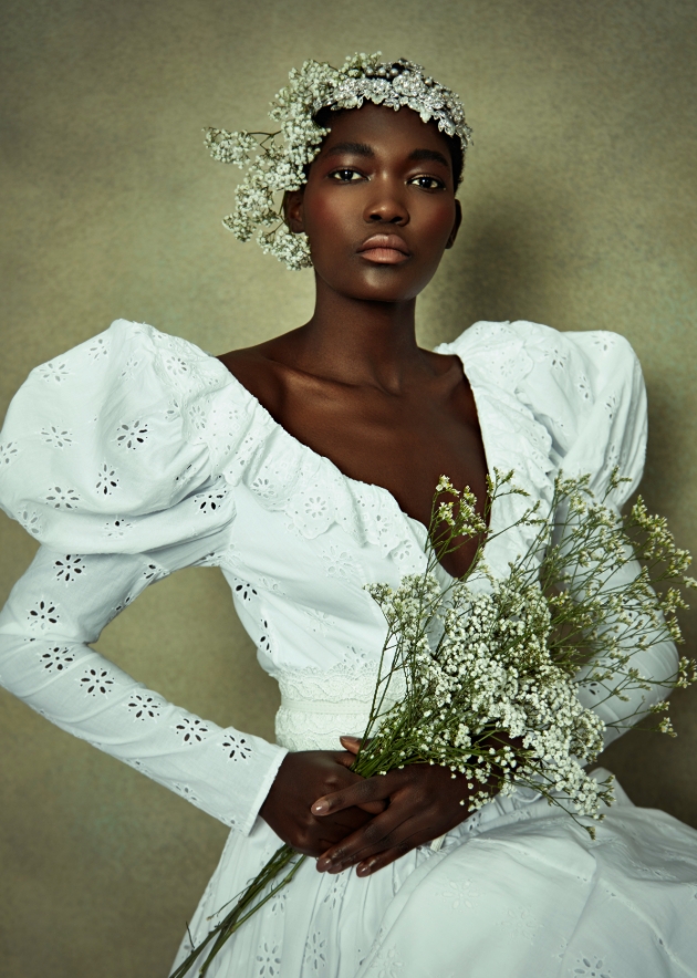 Model wears white cotton dress with puff sleeves and flower crown