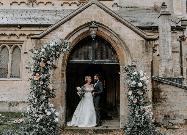 bride and grooms standing under church doorway