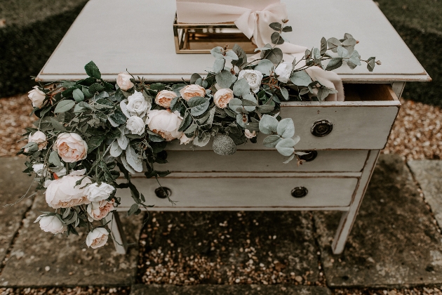 pale pink and green flowers displayed in old chest of drawers