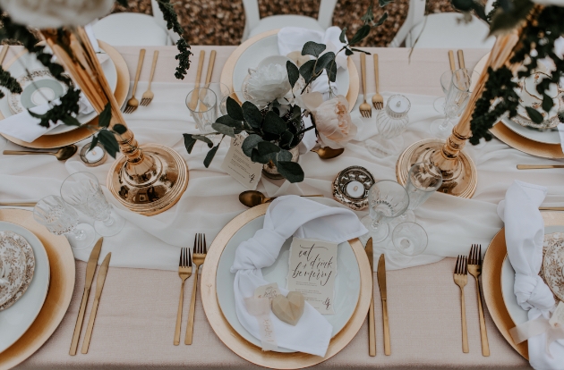 Table dressed for wedding with runner and rose gold cutlery and crockery