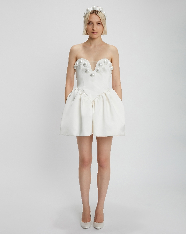 Model wears mini-length wedding dress with large pearl beads