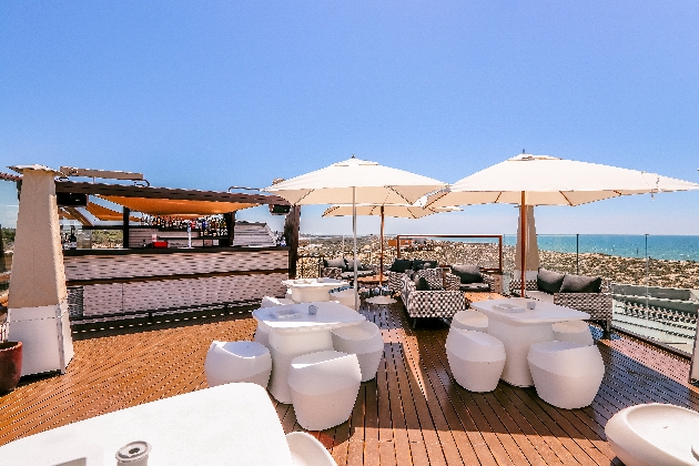 terrace with white seating an umbrellas and a bar with sea views