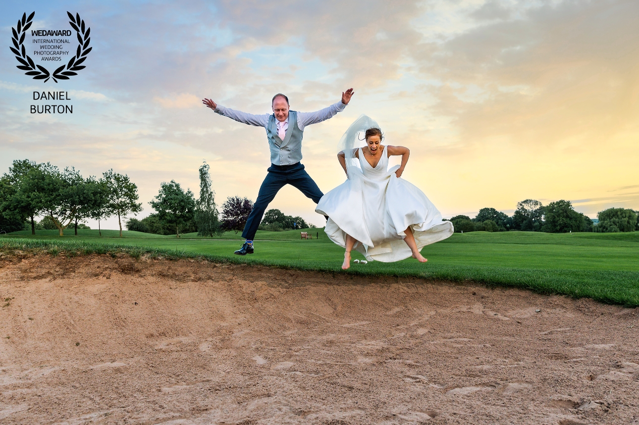 bride and groom jumping from gold green in to sand bunker
