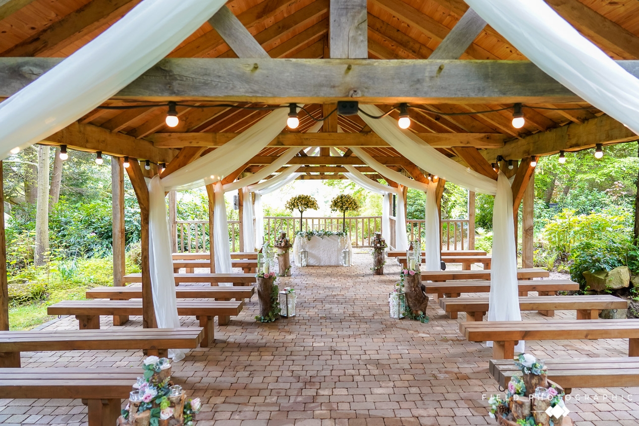 outdoor barn with no walls lots of beams draped in voile with benches for ceremony seating