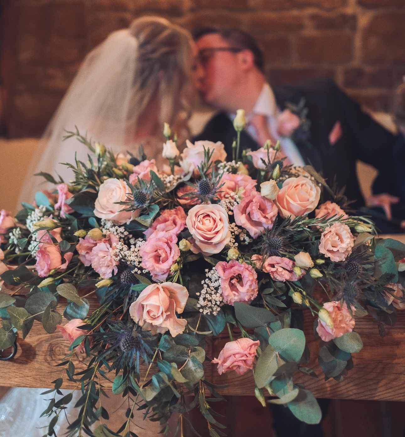 Bride's bouquet infront of couple kissing