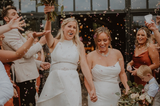 two brides leaving wedding covered in confetti