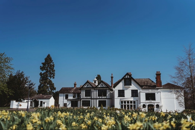 white and black manor house with lawn of daffodils in front