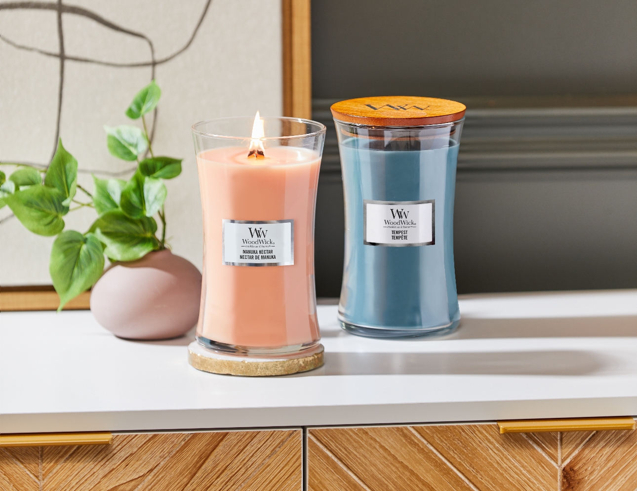 two tall candles with wood lids one in blush and one in blue