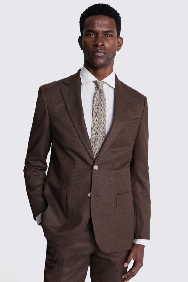 A man wearing a brown suit with a white shirt and patterned tie